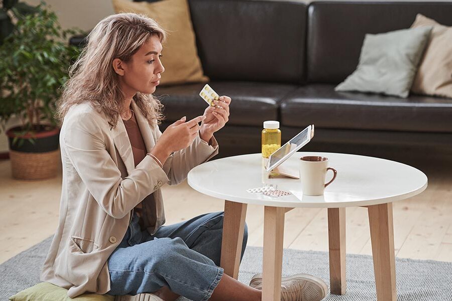 Is Cyclobenzaprine Addictive? A woman sitting near a table with medication in her hand.