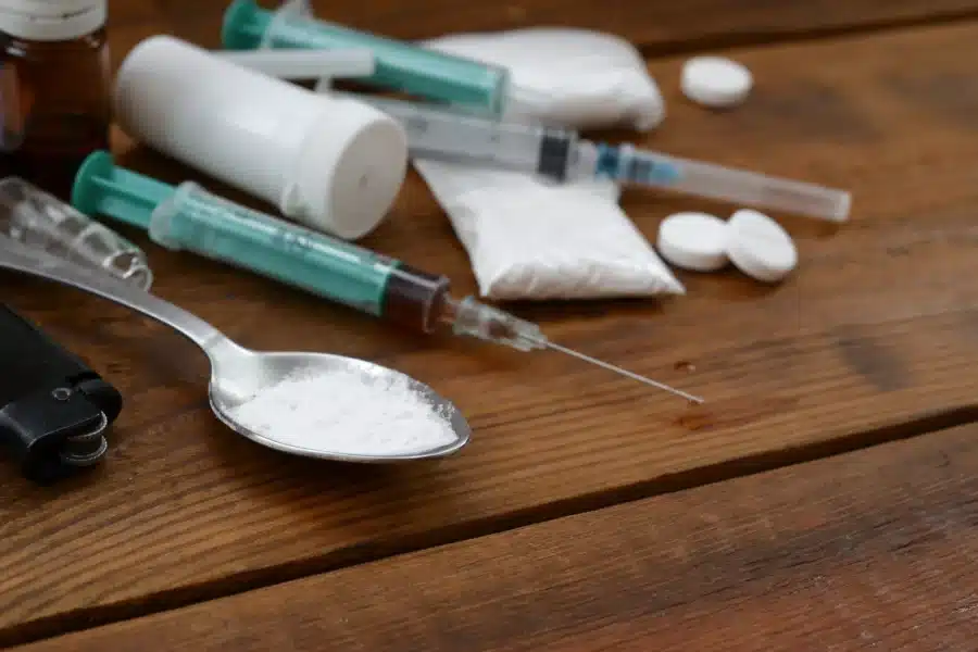 How Long Does PCP Stay In The System? A variety of drug paraphernalia on a wooden floor.