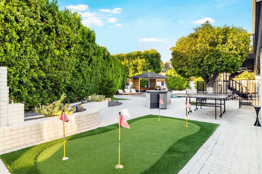 10-622-W-Palmaire-Ave-066 Backyard with a putting green, ping pong table, gazebo, lounge chairs, and lush greenery