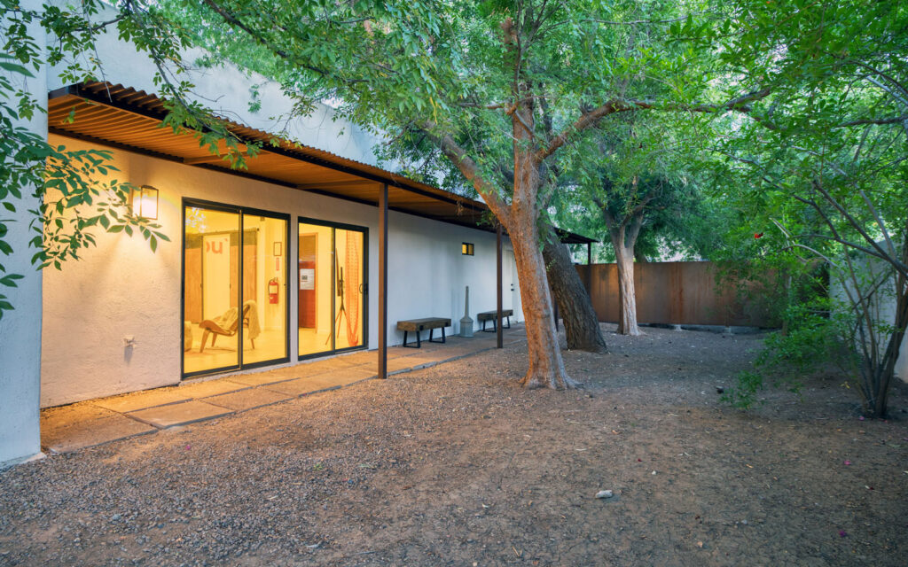4202-N-44th-St-Phoenix-601_1 Exterior view of a modern building with large glass doors, surrounded by trees and a dirt ground