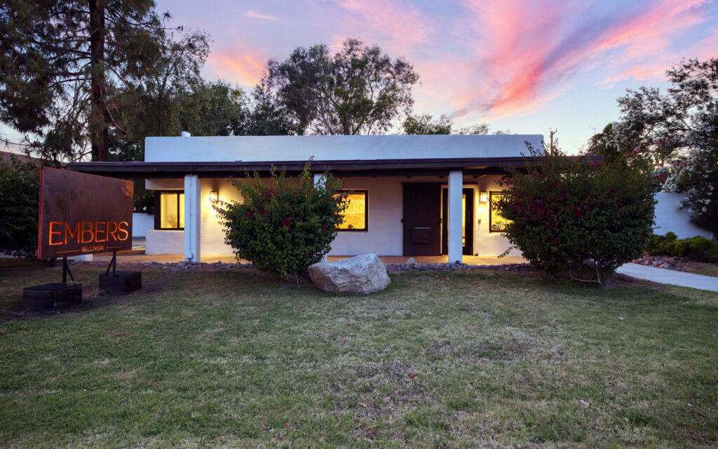 4202-N-44th-St-Phoenix-647_2 Single-story building with a sign reading "EMBERS RECOVER" on the lawn, surrounded by trees and bushes at sunset